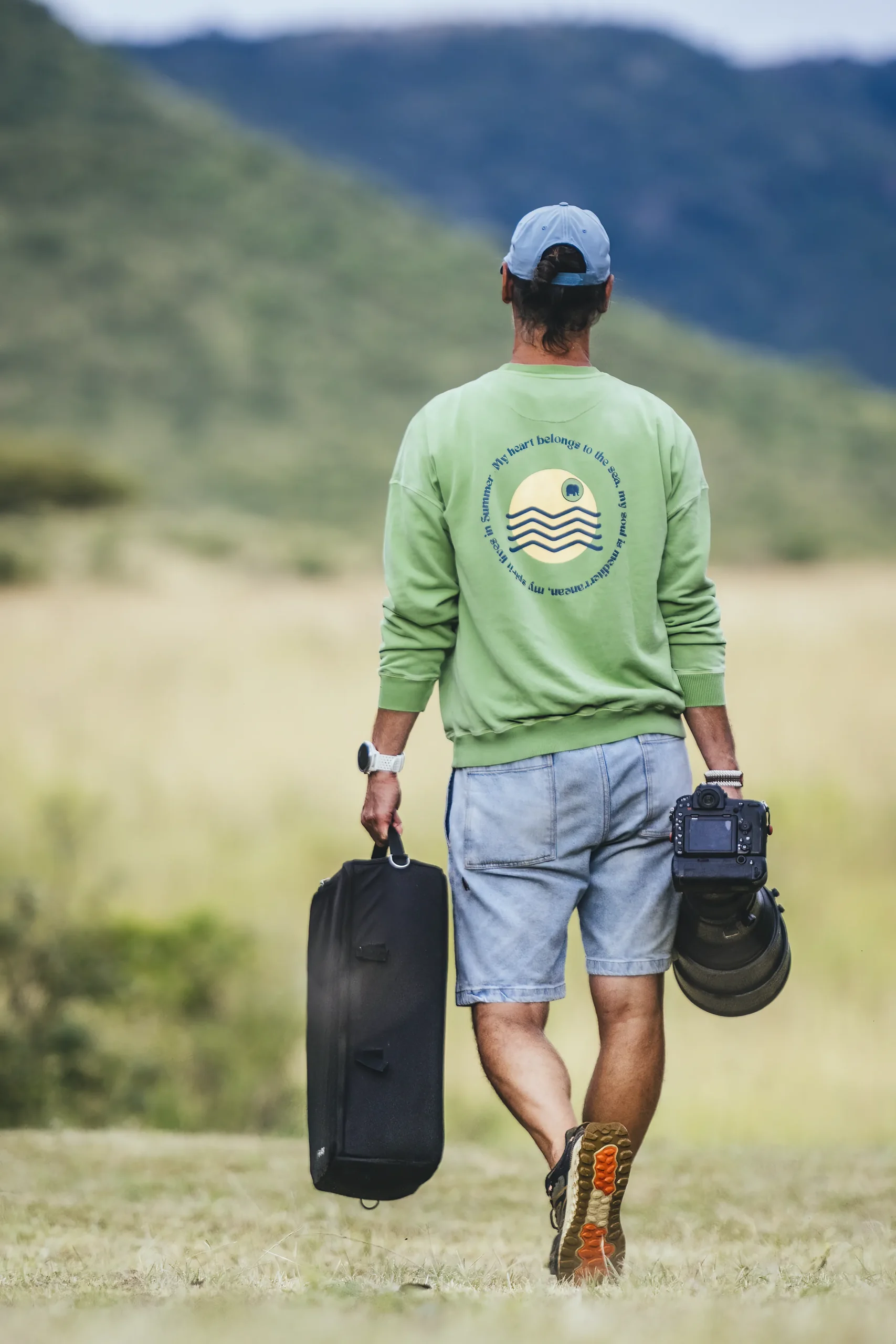 Nando Morales walking in the field carrying wildlife photography equipment